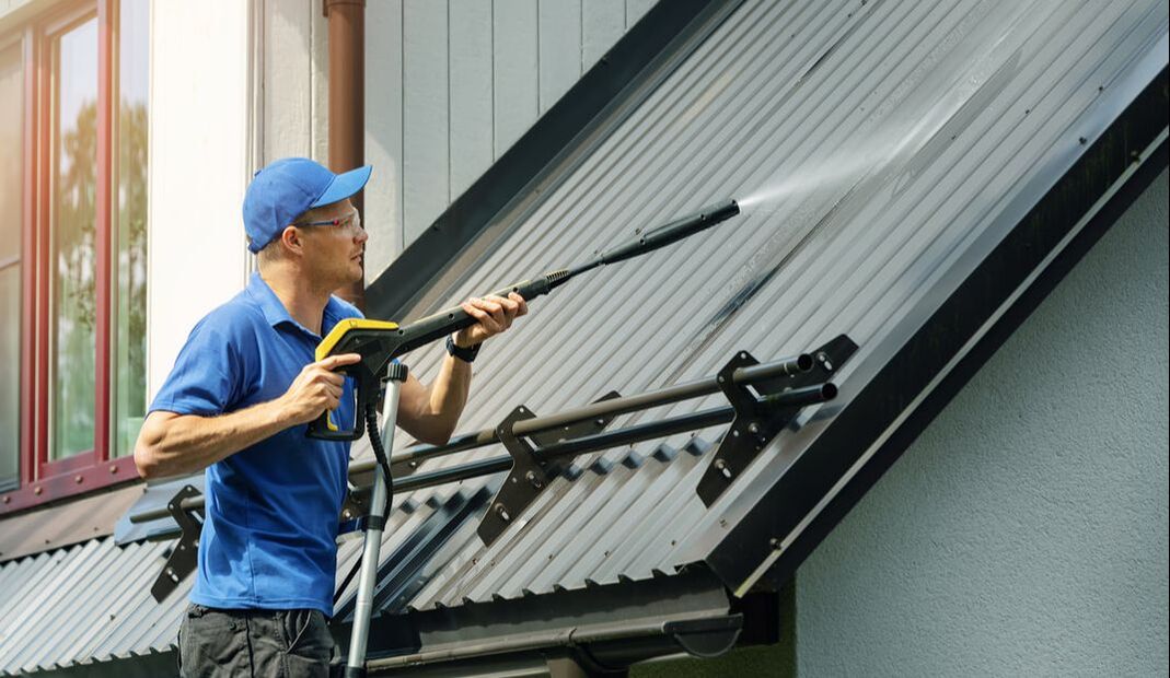 Picture of worker pressure washing a roof