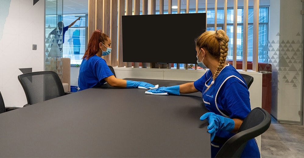 Picture of two women cleaning a table at work