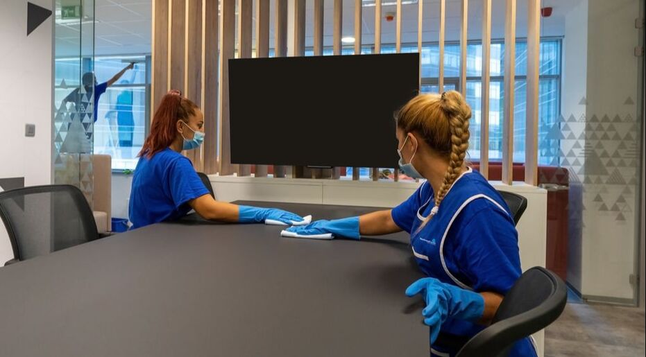 Picture of two janitors cleaning a desk at work